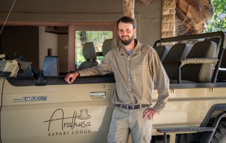 white-man-standing-next-to-a-brown-safari-vehicle