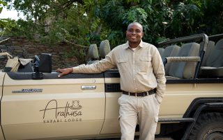 black-man-standing-next-to-a-brown-safari-vehicle